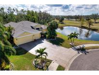 Aerial view of a single-Gathering home with a pond and golf course in the background at 9351 Raes Creek Pl, Palmetto, FL 34221