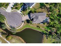 Stunning aerial view of a home featuring a screened pool, pond, manicured lawn, and circular driveway at 9351 Raes Creek Pl, Palmetto, FL 34221