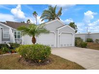 Two car garage with decorative landscape design including flowering plants, green shrubs, and palm trees at 502 Woodstork Cir, Bradenton, FL 34209