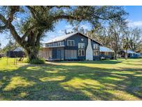 Dark-painted farmhouse with screened porch, surrounded by lush green lawn and mature trees at 14900 Coker Gully Rd, Myakka City, FL 34251