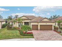 Single-story home with tile roof, two-car garage, and landscaped yard at 20345 Reale Cir, Venice, FL 34293