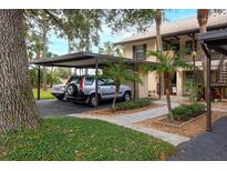 Condo parking area with covered carport and landscaping at 380 Three Lakes Ln # L, Venice, FL 34285