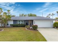 Updated home exterior boasts a gray and white color scheme, lush landscaping, and a two-car garage at 3866 Pin Oaks St, Sarasota, FL 34232