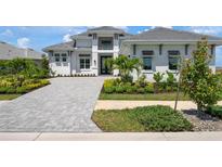 Beautiful two-story home with lush landscaping, a tiled roof, and a brick driveway at 624 Blue Shell Loop, Sarasota, FL 34240