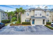 Tan two-story townhome with a teal door, two parking spots, and lush landscaping at 7664 Plantation Cir, Bradenton, FL 34201