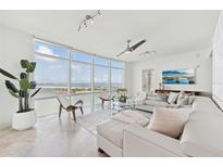 Bright living room features floor-to-ceiling windows with stunning water views and a comfortable white sectional sofa at 258 Golden Gate Pt # 801, Sarasota, FL 34236