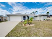 Single-story home with gray siding, white garage door, and landscaped lawn at 3215 Lake View Blvd, Port Charlotte, FL 33948