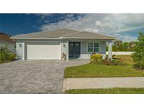 One-story home with white garage door, gray paver driveway, and landscaped lawn at 5252 Willow Lake Ct, Sarasota, FL 34233