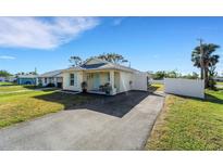 Cute bungalow with a fenced yard, driveway, and white gate at 585 Purdy St, Englewood, FL 34223