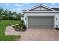 This home has a lovely exterior with a gray garage door and a brick paver driveway and walkway at 6005 Mesa Gln, Bradenton, FL 34203