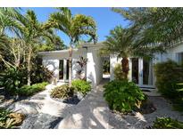 Landscaped entry with tropical plants and a walkway leading to the home's entrance at 6061 Gulf Of Mexico Dr, Longboat Key, FL 34228