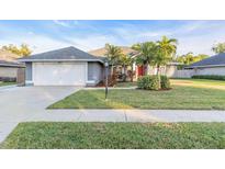 Charming single-story home featuring a well-manicured lawn, palm trees, and a two-car garage at 4877 Post Pointe Dr, Sarasota, FL 34233