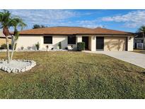 Single-story home with a beige exterior, brown roof, and landscaped lawn at 25484 Terrain Ln, Punta Gorda, FL 33983