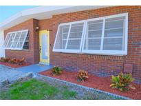 Charming brick home featuring a vibrant yellow front door and beautifully landscaped flower beds at 5611 26Th W St, Bradenton, FL 34207