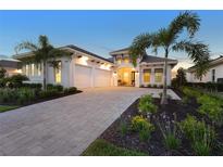 Beautiful home featuring a paver driveway, lush landscaping, and a three-car garage at 8328 Sea Glass Ct, Sarasota, FL 34240