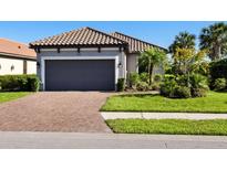 Single-story home with gray garage door, tile roof, and landscaped lawn at 8752 Bellussi Dr, Sarasota, FL 34238