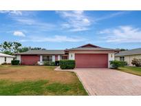 Ranch-style home with red siding, brick driveway, and well-manicured lawn at 4423 Meadow Creek Cir, Sarasota, FL 34233