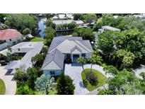 Aerial view of a beautiful home with a gray roof, lovely landscaping, and a circular driveway at 4815 Featherbed Ln, Siesta Key, FL 34242