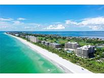 Beautiful aerial view of beachfront condominiums with pristine white sand and turquoise water at 575 Sanctuary Dr # A303, Longboat Key, FL 34228