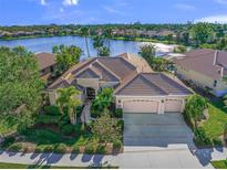 Stunning lakefront home featuring manicured landscaping, a three-car garage, and a tile roof at 518 Luminary Blvd, Osprey, FL 34229