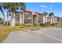 Exterior view of condo with manicured landscaping, red roof, and screened in balconies at 3267 Beneva Rd # 201, Sarasota, FL 34232