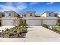 Charming townhome featuring a spacious two-car garage, red door, and fresh landscaping at 5658 Silverbridge Trl, Bradenton, FL 34211