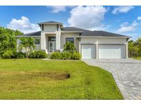 Single-story home with two-car garage, lush landscaping, and a paved driveway at 0 Symco Ave, North Port, FL 34286