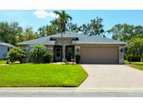 Inviting single-story home features a well-manicured lawn, mature landscaping, and a brick-paved driveway leading to a two-car garage at 5115 44Th St W, Bradenton, FL 34210