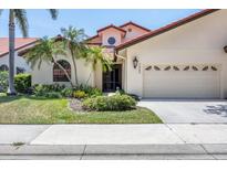 Exterior of charming house with lush landscaping, a two-car garage, and inviting entryway at 7242 Villa D Este Dr, Sarasota, FL 34238