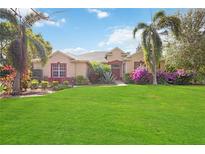 One-story home with landscaped yard, palm trees, and a large lawn at 22435 Panther Loop, Bradenton, FL 34202