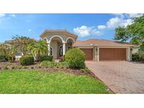 Inviting home featuring a manicured lawn, mature landscaping, and a paver driveway leading to a three-car garage at 2886 Grazeland Dr, Sarasota, FL 34240