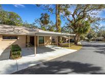 Covered carport with concrete parking pad and lush landscaping at 4964 Village Gardens Dr # 142, Sarasota, FL 34234