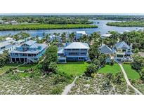Stunning coastal home with manicured lawn, mature palms, and boat dock access on a waterway at 506 S Casey Key Rd, Nokomis, FL 34275
