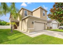 Two-story house with beige exterior, two-car garage, and manicured lawn at 1964 Hawks View Dr, Ruskin, FL 33570
