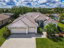 Stunning single-story home featuring a three-car garage, tile roof, and beautifully landscaped front yard at 2737 Harvest Dr, Sarasota, FL 34240