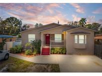 Tan house with red door, landscaping, and driveway at 4704 Town N Country Blvd, Tampa, FL 33615