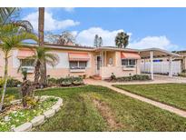 Charming single-story home with colorful awnings, manicured lawn, and a convenient carport at 550 80Th Ave, St Pete Beach, FL 33706