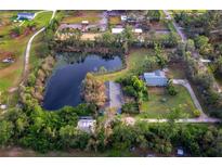 Expansive aerial view of a serene property featuring a large pond, lush greenery, and charming homes at 5645 Churchill Downs Rd, Sarasota, FL 34241
