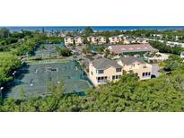 Breathtaking aerial view of community featuring tennis courts, a clubhouse, and lush landscaping at 653 Cedars Ct, Longboat Key, FL 34228