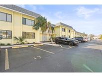 A two-story condo building with light yellow paint, grey roof, and a parking lot at 6703 Midnight Pass Rd # 108B, Sarasota, FL 34242