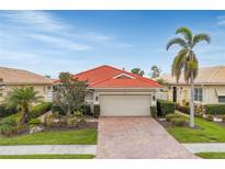 Charming home featuring a red tile roof, brick driveway, two-car garage, and well-maintained landscaping at 150 Mestre Pl, North Venice, FL 34275