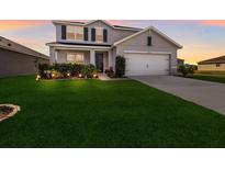Charming two-story home showcasing a lush green lawn and well-maintained landscaping at 15404 Trinity Fall Way, Bradenton, FL 34212