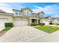 Inviting townhome featuring a two-car garage, brick-paved driveway, and manicured lawn at 3640 Tin Cup Blvd, Sarasota, FL 34232