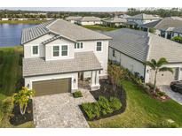 Beautiful two-story home with a gray tiled roof, brick driveway, and well-maintained landscaping at 3704 Wild Blossom Pl, Parrish, FL 34219