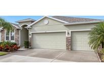 Attached two car garage with stone accents complementing the light green exterior paint of the home at 452 Tierra Verde Way, Bradenton, FL 34212