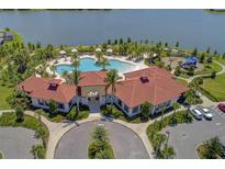 Aerial view of a community pool, lake, playground, and recreation center with red tile roof and manicured lawns at 5447 Tripoli Dr, Palmetto, FL 34221