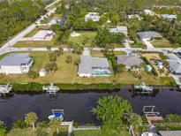 Aerial view of a waterfront home with a screened pool and lush landscaping along the canal at 9008 Allapata Ln, Venice, FL 34293