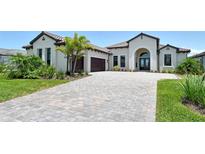 Beautiful single Gathering home boasts a paver driveway, two car garage, manicured lawn, and a tile roof at 10612 Nicklaus Ct, Englewood, FL 34223