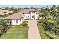 Stunning home with a beautiful brick driveway, lush landscaping, and an elegant, light-colored exterior with a tile roof at 11740 Rive Isle Run, Parrish, FL 34219