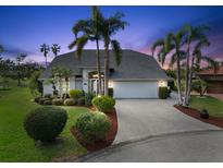 Charming single-story home featuring a two-car garage, landscaped yard, and mature palm trees during twilight at 6170 Misty Oaks Dr, Sarasota, FL 34243